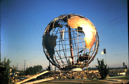 Globe being installed, workers mid way up the wall.